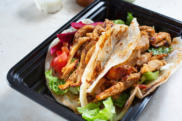 A view of a plastic container of chicken shawarma wraps.