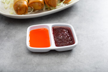 A view of a double compartment condiment cup, featuring sweet sour sauce and plum sauce.