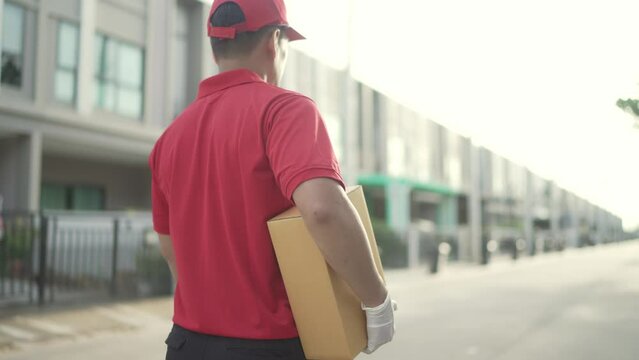 Back view. Delivery man holding parcel boxes finding Customer home Village.