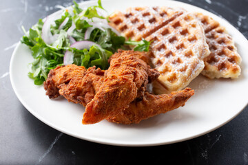 A view of a plate of chicken and croffle.