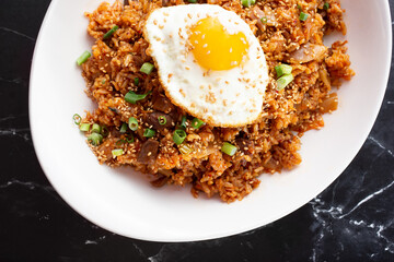 A top down view of a plate of kimchi fried rice, featuring a fried egg.