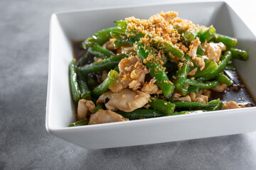 A closeup view of a bowl of chicken and garlic green beans.