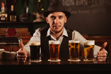 happy smiling bartender at bar counter with four glasses of various draft beer in pub