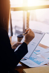 Asian Business woman using calculator and laptop for doing math finance on an office desk, tax, report, accounting, statistics, and analytical research concept