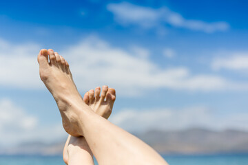 Vacation holidays. Woman feet closeup of girl relaxing on beach on sunbed enjoying sun on sunny summer day.