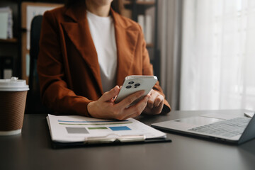 Fototapeta premium Businesswoman hand using smart phone laptop and tablet with social network diagram on desk as concept in morning light..