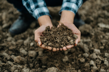 Oldman farmer holding soil in cupped hands.