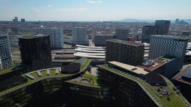Aerial revealing shot of Vienna Hbf Train Station surrounded by grass-covered buildings, Wien, Austria