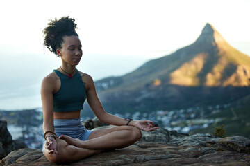 Fototapeta premium Woman, mediation and yoga on a mountain with wellness in cape town for fitness and health. Female hiker, calm and meditating on a cliff in the outdoor with nature cityscape for healthy body.