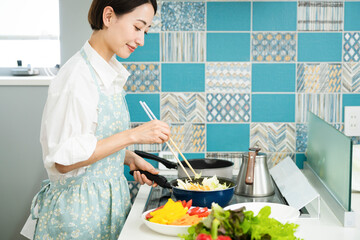 野菜炒めを作る若い女性　料理イメージ © aijiro