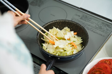 野菜炒めを作る若い女性　料理イメージ