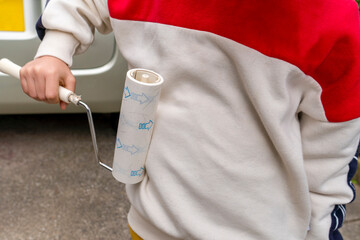 粘着クリーナーで衣服を綺麗にしている男の子。コロコロ転がして掃除するアイテム。小学生の子供