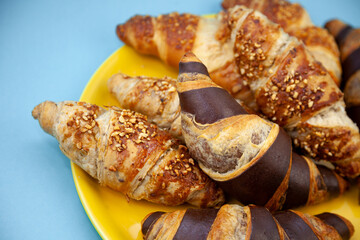 Chocolate croissants or croissant with nut crumbs on a plate. Delicious breakfast on the table. Tasty sweet baking dessert for coffee. Food background. Fresh buttery croissants rolls