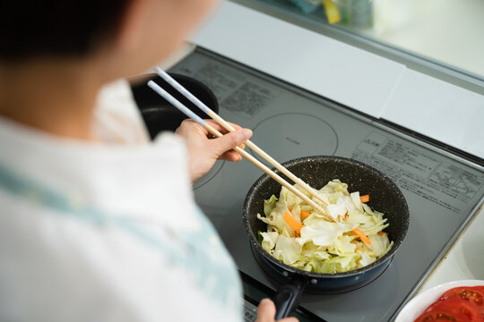 野菜炒めを作る若い女性　料理イメージ