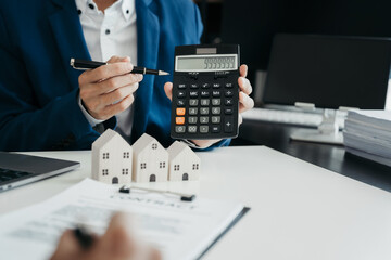 home loan officer uses a calculator with a house plan