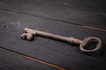 Old antique rusty key on dark wood texture background