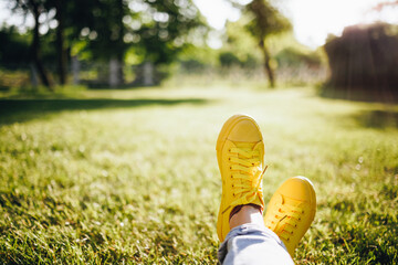 Youth sneakers on girl legs on grass during sunny summer day