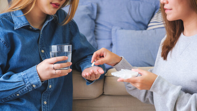 Closeup image of a woman holding and giving pills to her friend