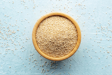 Quinoa in a bowl, healthy organic wood, uncooked, shot from the top on a blue background