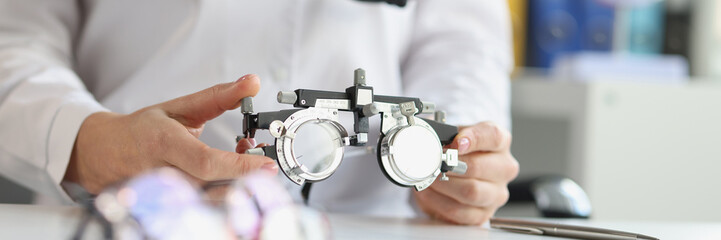 Ophthalmologist with trial frame for selection of complex astigmatic glasses. Selection of lenses...