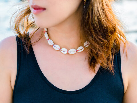 Beautiful shell necklace on Asian woman's beauty skin neck who wearing black tank top. Close-up braid seashell necklace beach, choker jewellery asian tropical summer accessory fashion style.