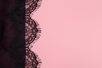 Black lace on silk clothes on a pink background. copy space for text