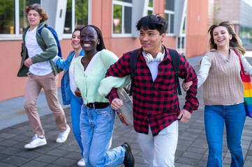 Teen students run arm in arm to school, first day of high school in September, young people and happy to start the new school year