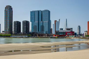 Fototapeta na wymiar Rotterdam, The Netherlands, June 5, 2023: the towers on Wilhelmina Pier reflecting in puddles on the temporary beach of the Rijnhaven land reclamation project