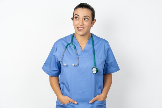 Amazed Young doctor woman wearing blue uniform over isolated background bitting lip and looking tricky to empty space.