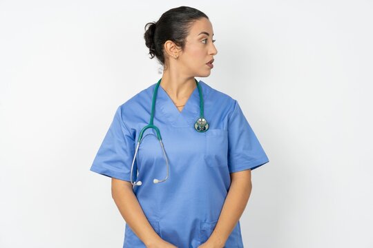 Close up side profile photo Young doctor woman wearing blue uniform over isolated background not smiling attentive listen concentrated