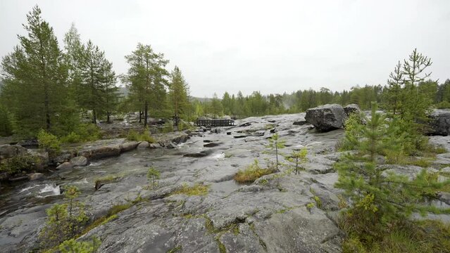 Water flows over shield rock at Storforsen waterfall on rainy day