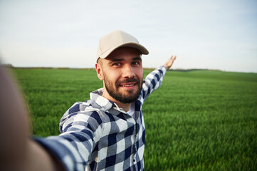 Making selfie. Handsome young man is on agricultural field