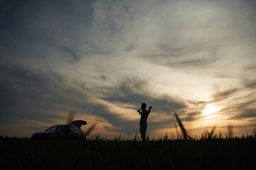 Silhouette of a man that is in the field at sunset time. Dramatic sky