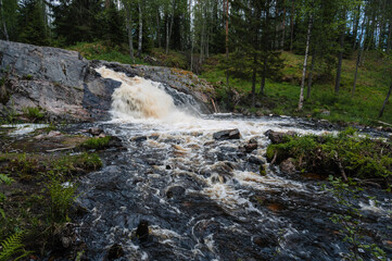 waterfall in river with stones in forest in summer on cloudy day