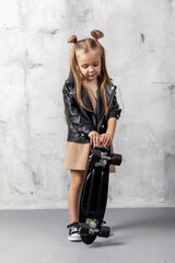 Stylish cool little girl child with skateboard over grey background