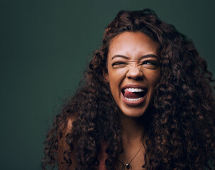 Natural beauty, tongue out and wink by gen z girl with hair, curly and fun on green background. Afro, hair care and female model flirt, emoji and silly face, personality or youth aesthetic in studio - obrazy, fototapety, plakaty