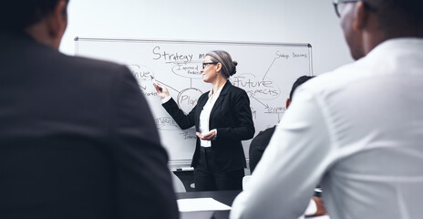 Business woman, coaching and presentation on whiteboard in meeting for strategy or planning at office. Female person, CEO or coach training staff in project plan or team brainstorming at workplace