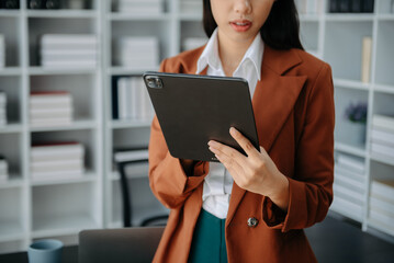 Fototapeta premium Businesswoman hand using laptop, tablet and smartphone in office. Digital marketing media mobile app and discussing plan new start up project.