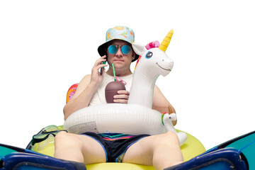 man equipped for the pool with cap, sunglasses, unicorn float, coconut drink, snorkel fins talking on the phone