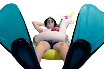 full shot, man equipped with unicorn float, mirrored glasses, beach cap, snorkel fins sitting on a large float and sunbathing