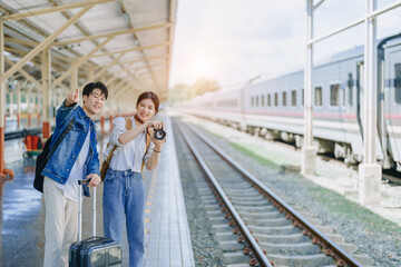 Young couple traveling using a camera to capture memories while waiting for the train at the station.travel concepts.