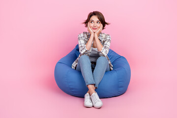 Obraz na płótnie Canvas Full body portrait of minded positive lady sit comfy bag arms touch cheekbones look empty space isolated on pink color background