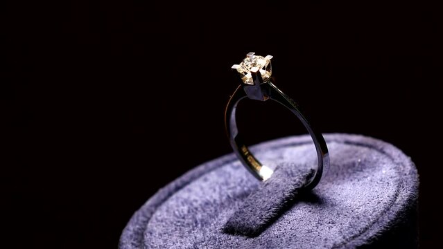 View of design gold diamond solitaire ring on black background in dark