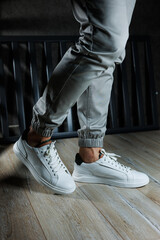 Casual white sneakers for men. Male legs in white leather summer shoes. Comfortable men's white...