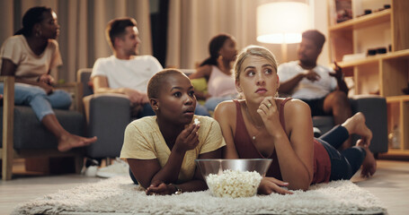 Friends, popcorn and movie at home at night for entertainment and relaxing for enjoyment. Friend, together and watching tv in the lounge with a snack in the evening to relax on the weekend for fun.