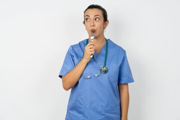 Photo of dreamy Beautiful doctor woman standing over white studio background lick fork look empty...