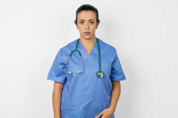 Displeased Beautiful doctor woman standing over white studio background frowns face feels unhappy has some problems. Negative emotions and feelings concept
