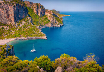 Naklejka premium Marvelous view of Damos Beach with luxury yacht in the bay. Superb summer scene of Peloponnese peninsula, Greece, Europe. Nice morning seascape of Myrtoan Sea. Vacation concept background.