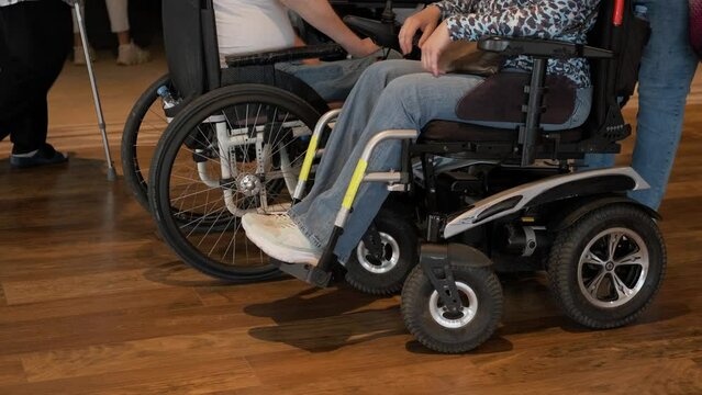 A group of disabled people in modern wheelchairs stand in the hospital and communicate with each other unrecognizable