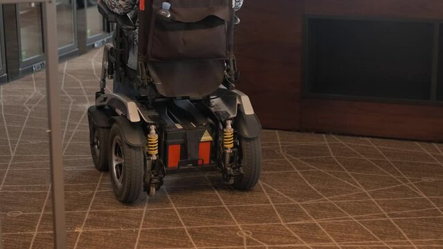 A woman in an electric wheelchair moves through a modern well-equipped hospital. Medicine and accessible environment